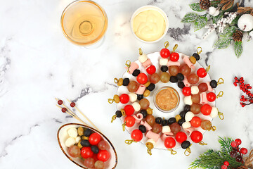 Christmas and New Year's dishes, a set of snacks and refreshing drinks for the festive table. A plate with canapes of tomatoes, mozzarella cheese, olives, black olives and grapes on a marble table,