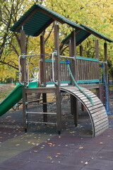 wooden slide on the playground in the city park in autumn against the background of tree branches