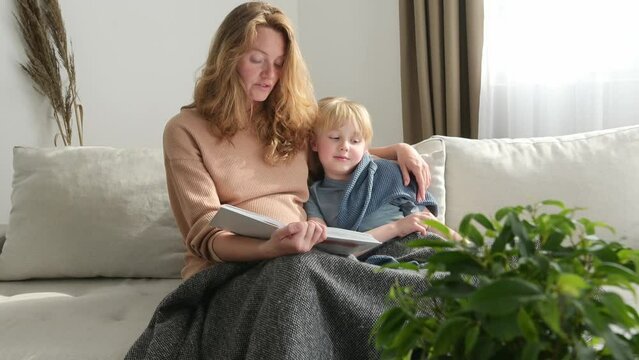 Cute pregnant mom reading a book to her eldest son. Quality parenting time with children. Cozy home moment with mother and her boy. Reading fairy tales and adventure stories for child for baby