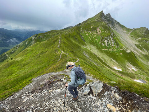 EIne Frau geht bergab mit Wanderstöcken bei Fügen im Zillertal in Österreich während Alpenüberquerung
