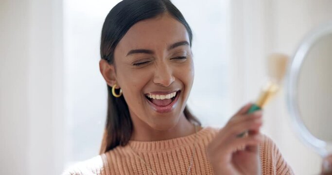 Woman, skincare and makeup brush on face and mirror at home with cosmetics, foundation and happiness. Beautiful model, indian and application of beauty products with aesthetic, wink or cosmetology