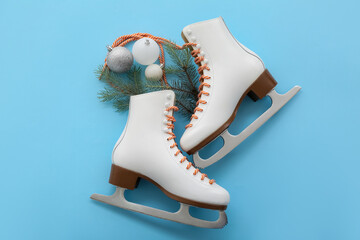 Ice skates with Christmas balls and fir branches on blue background