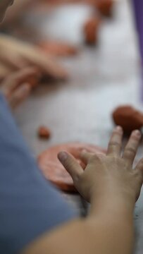 Children are sculpting with clay on a wooden craft table.