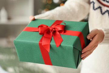 Woman giving gift box at home on Christmas eve, closeup
