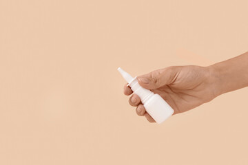 Woman with nasal drops on beige background