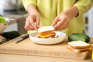 Woman making tasty sandwich in kitchen, closeup