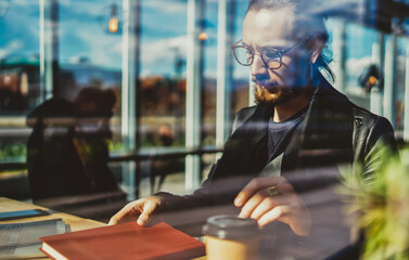  young hipster guy in trendy eyeglasses studying indoors with literature book