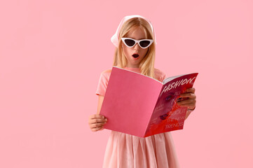 Little girl reading fashion magazine on pink background