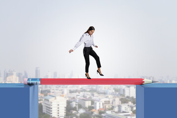 Attractive young european businesswoman crossing pencil bridge on sky background. Career problem...