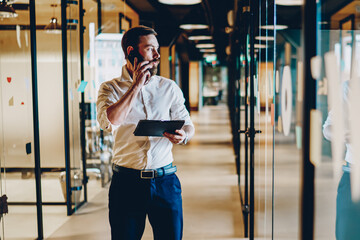 Entrepreneur standing in office corridor and talking on cellphone