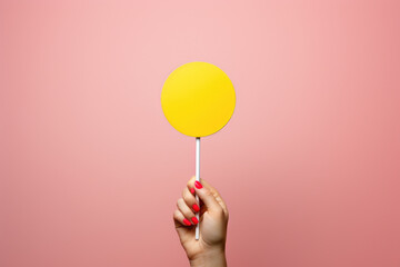 Person holding yellow lollipop in front of vibrant pink background. This image can be used to depict sweetness, enjoyment, or treat for special occasions. - Powered by Adobe