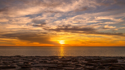 A sunset over the sea with a rocky foreground in the tropics at Karumba in Australia.