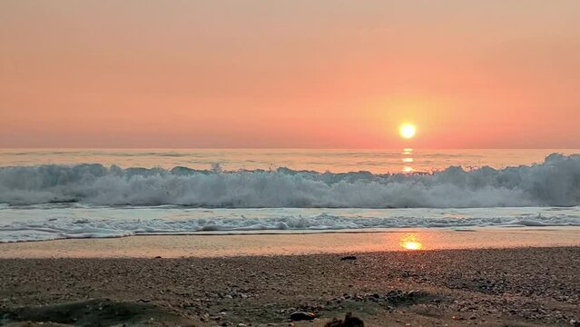 High sea waves on background of pink sunset