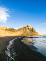 Northern scenery along ocean shore with massive Vestrahorn mountain peaks in Iceland. Famous Stokksnes seashore with icelandic black sand beach and nordic surroundings, natural skyline.
