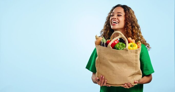 Volunteer woman, vegetables and donate in studio, smile and face for food product for charity by blue background. Girl, bag and happy for helping, care and mockup space for gift, kindness or portrait