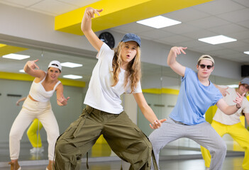 Energetic teenage girl wearing cap engaging in breakdance in dance studio. Teenagers training...