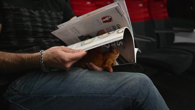 On the train, a man flips through a magazine, men's hands flip through a magazine in close-up