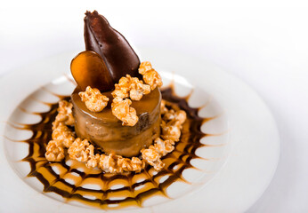 Delicious chocolate cake decorated with Carmel, Popcorn, and chocolate sauce on white plate
