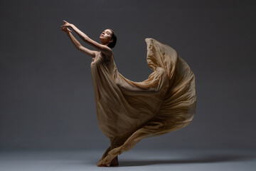 girl dancer in a long beige dress on a dark background