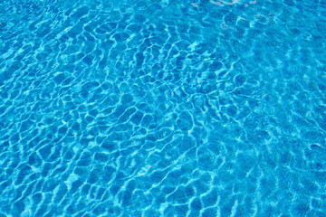 Blue water in summer pool on bright sunny day. Background. Clean transparent water with reflection.