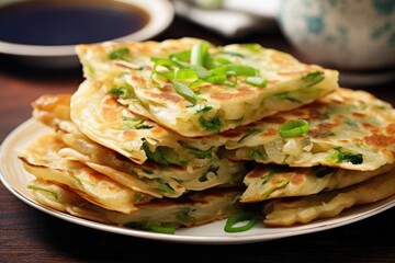 A tempting photograph capturing a plate of crispy and golden Chinese scallion pancakes, displaying the layers of flaky dough infused with a savory green onion aroma.