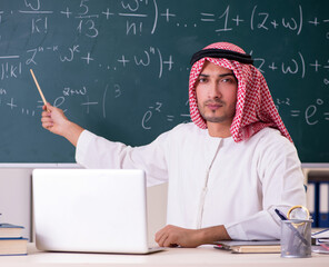 Arab teacher in front of chalkboard