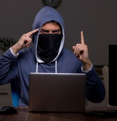 Male hacker hacking security firewall late in office