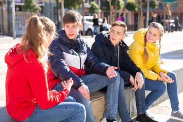 Group of modern teenagers hanging out on streets of city on warm spring day..