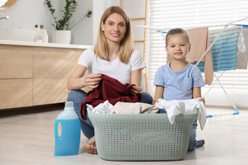 Mother and daughter taking out dirty clothes from basket in bathroom