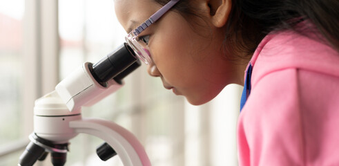 Children scientist learning on biology and chemistry in the laboratory. A STEM education learning concept. An Asian student girl using microscope in a STEM class lab.