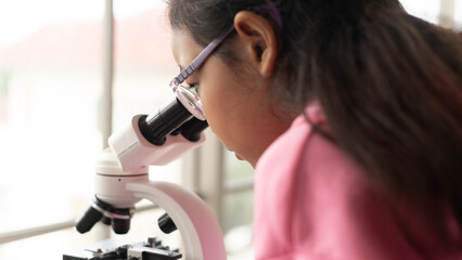 Children scientist learning on biology and chemistry in the laboratory. A STEM education learning concept. An Asian student girl using microscope in a STEM class lab.