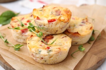 Delicious egg muffins with cheese and bacon on wooden board, closeup