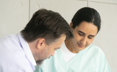 Fototapeta premium Caucasian male physician diagnosis for root cause finding with Hispanic female patient. Knee injury problem. The medical healthcare exam and check-up with the doctor concept.