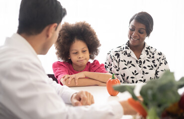 Hispanic nutritionist doctor consulting mixed-race child with her African American mother about a...