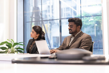 An Indian businessman using a laptop with businesswoman in a group of diversity business people colleagues meeting at the office.