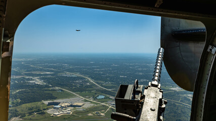 looking out right gun position of B-24 Liberator with machine gun in foreground and P-51 Mustang...