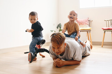 Two adorable Asian little kids playing with lovely dad at home