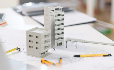 Architectural model on desk with laptop, drawing technical tools and blueprints. Architecture, building, construction and real estate business.