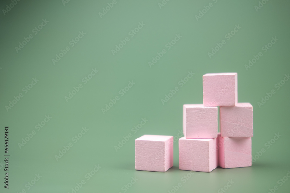 Wall mural Stacked pink colored wood building blocks on a green background