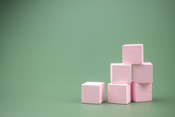 Stacked pink colored wood building blocks on a green background
