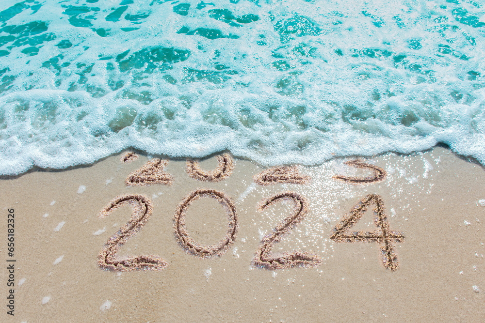 Wall mural message year 2023 replaced by 2024 written on beach sand background. good bye 2023 hello to 2024 hap