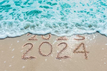  Message Year 2023 replaced by 2024 written on beach sand background. Good bye 2023 hello to 2024 happy New Year coming concept. © MAITREE