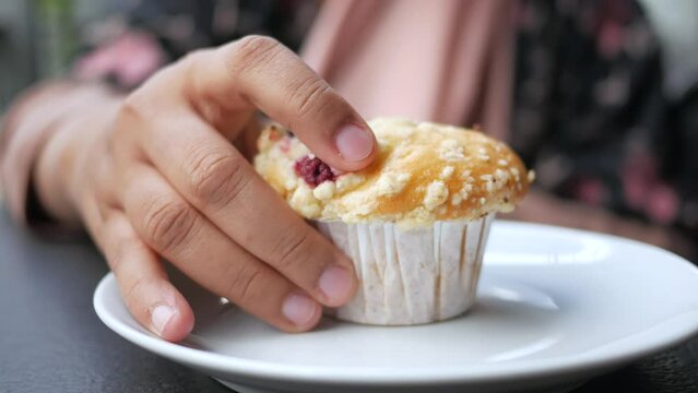  women hand pick a chocolate muffin on table 