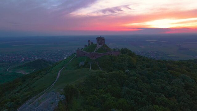 Aerial view of the ruins of a medieval citadel located in Siria, Arad county, Romania. Footage was done from a drone while flying forward above the ruins at sunset.