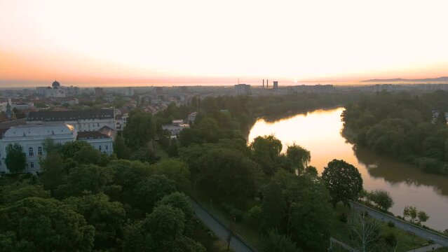 Aerial footage over Arad city center, above the park and the river Mures. Video was shot from a drone, in the morning at sunrise, while flying with camera level.