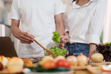 Couple making food or salad in the kitchen at home.