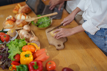 Couple cutting potatoes to cook or make salad in home kitchen.