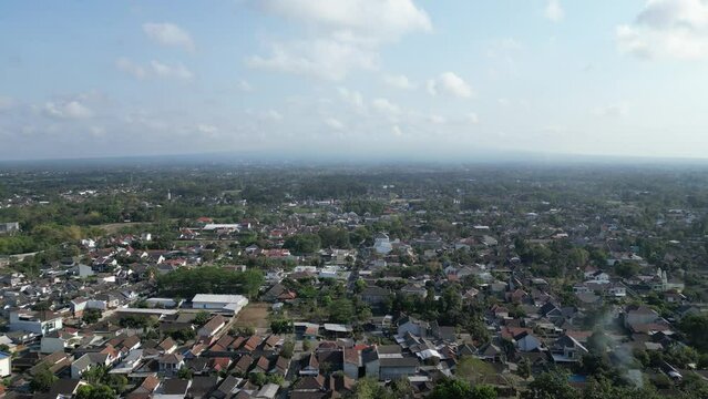 Aerial view of Jogja City with buildings, crowded vehicles traffic in morning sunlight. Sleman cityscape urban landscape. Population density is displacing agricultural land and forests.