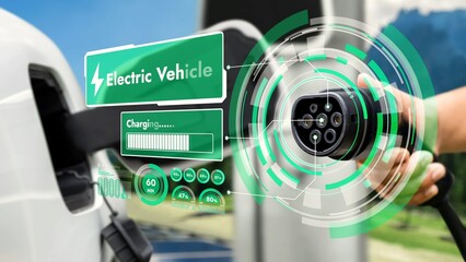 Focus EV charger pointing in front of camera display eco-friendly icon pictogram hologram with blur natural background. EV car charger plug using alternative clean energy reducing CO2 emission.Peruse