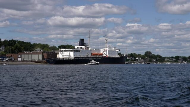 State of Maine open ocean ship docked at pier as smaller boat circles